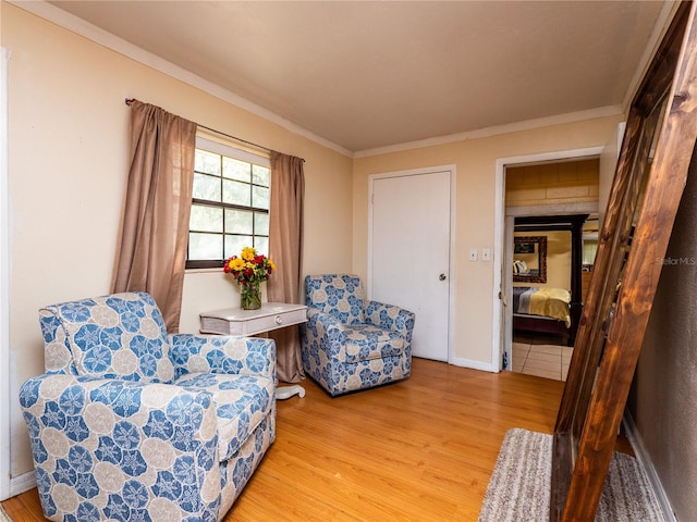 living area with crown molding and light hardwood / wood-style flooring