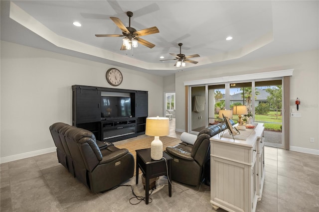 living room with ceiling fan and a tray ceiling