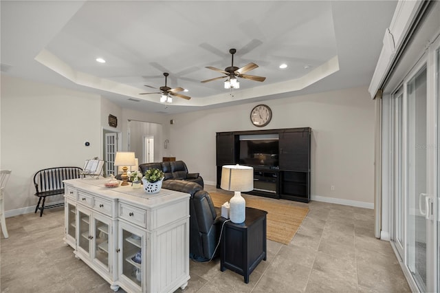 living room featuring a tray ceiling and ceiling fan