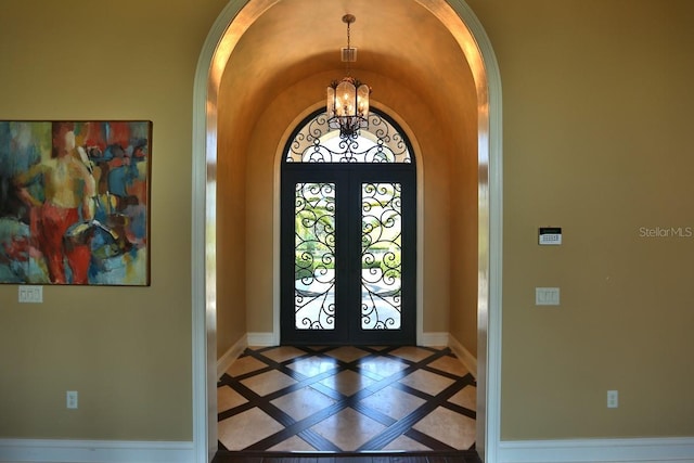 foyer with french doors, lofted ceiling, and a notable chandelier