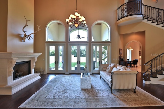 living room with dark wood-type flooring, a high ceiling, a chandelier, and french doors