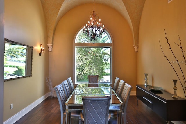 dining room with dark wood-type flooring, a chandelier, and lofted ceiling