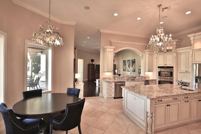 kitchen featuring a center island with sink, crown molding, stainless steel appliances, hanging light fixtures, and sink