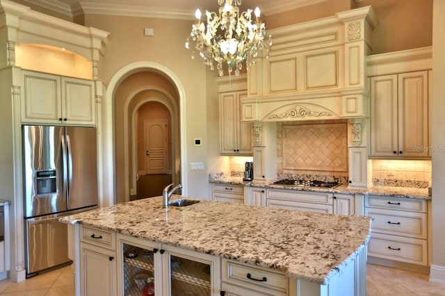 kitchen with cream cabinets, a center island with sink, stainless steel appliances, pendant lighting, and sink