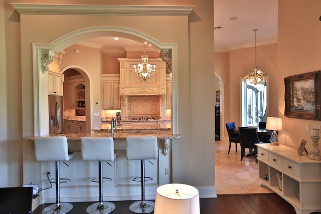 kitchen with dark hardwood / wood-style flooring, stainless steel fridge with ice dispenser, ornamental molding, light stone countertops, and decorative light fixtures