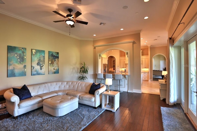 living room with ornamental molding, dark wood-type flooring, and ceiling fan