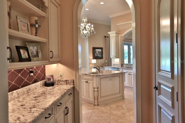 bar with cream cabinets, sink, ornamental molding, light stone countertops, and pendant lighting