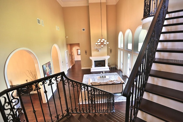 stairway featuring wood-type flooring, a notable chandelier, and a towering ceiling