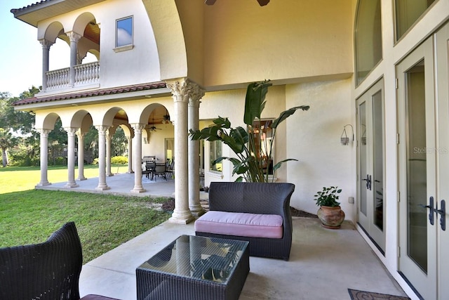 view of patio with ceiling fan and a balcony