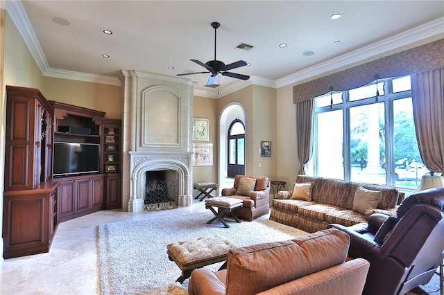 living room featuring ceiling fan, a large fireplace, and crown molding