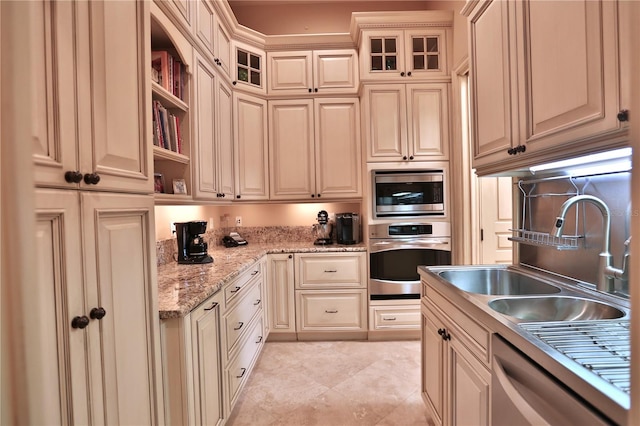 kitchen featuring light stone countertops, sink, cream cabinetry, and stainless steel appliances