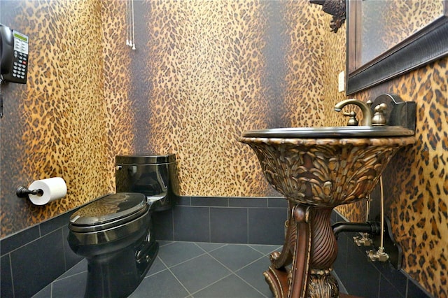 bathroom with tile patterned floors, toilet, and tile walls