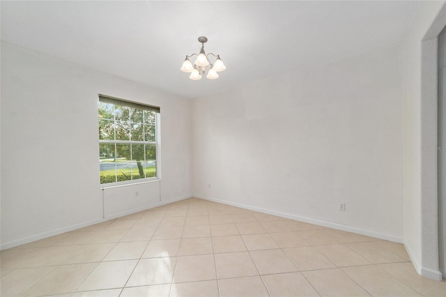 tiled spare room featuring a chandelier