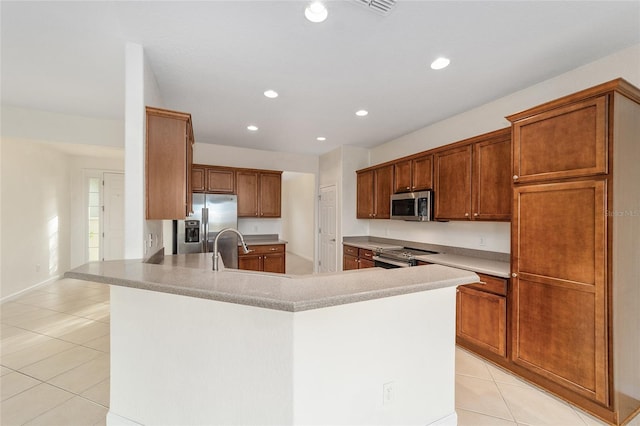 kitchen with kitchen peninsula, sink, light tile patterned floors, and appliances with stainless steel finishes