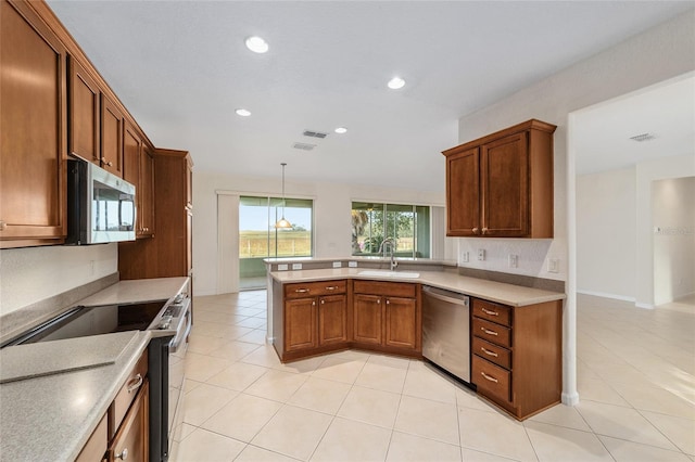 kitchen with kitchen peninsula, appliances with stainless steel finishes, sink, light tile patterned floors, and decorative light fixtures