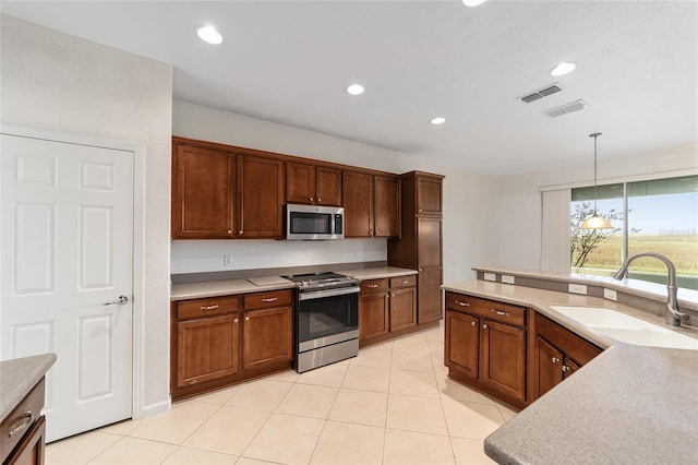 kitchen with pendant lighting, sink, light tile patterned floors, and stainless steel appliances