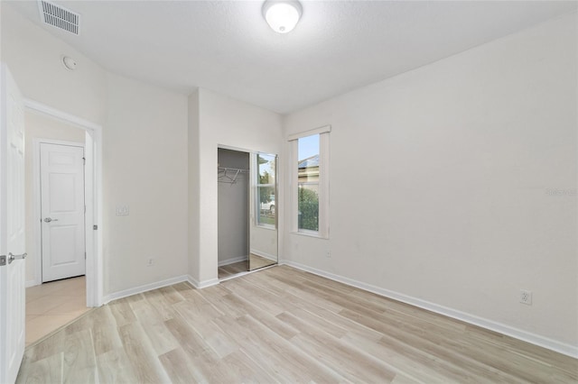 unfurnished bedroom featuring light hardwood / wood-style floors, a textured ceiling, and a closet