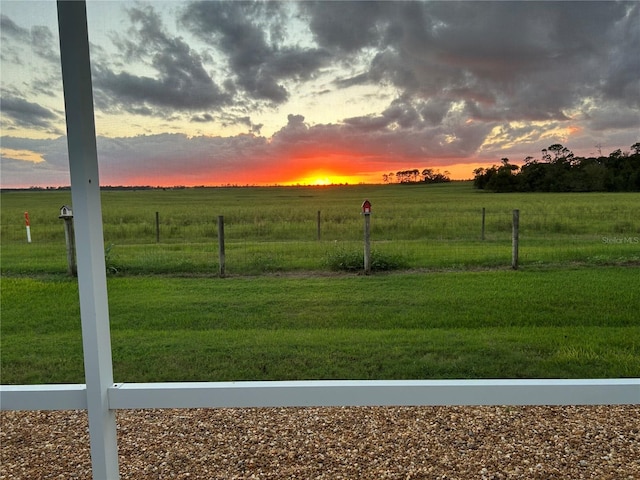 yard at dusk featuring a rural view