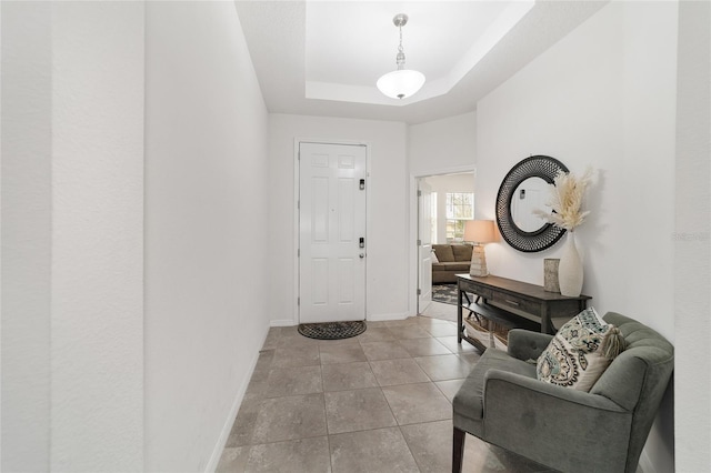 tiled entrance foyer with a tray ceiling