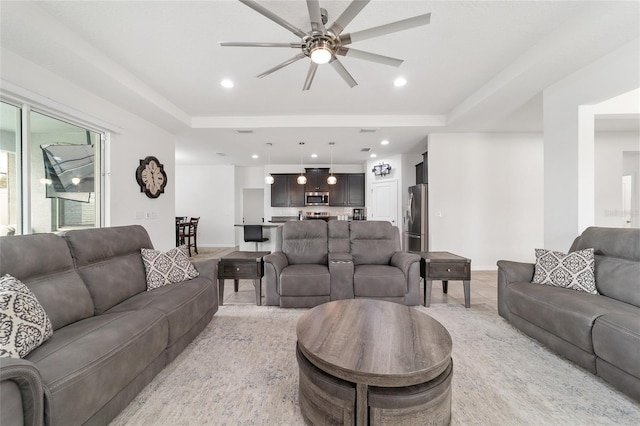 living room featuring ceiling fan and a raised ceiling