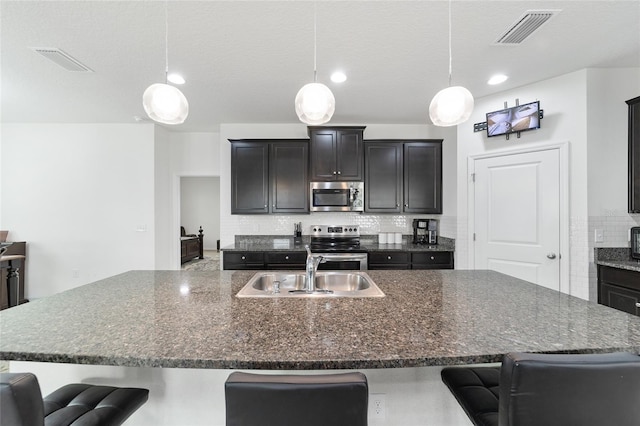 kitchen featuring stainless steel appliances, a breakfast bar, sink, and pendant lighting