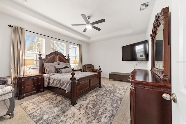 carpeted bedroom featuring ceiling fan and a tray ceiling