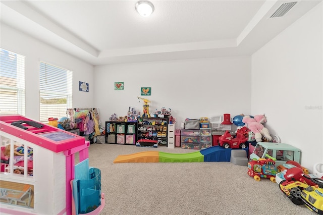 playroom featuring carpet and a raised ceiling