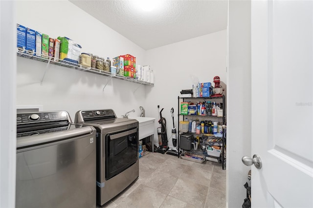 clothes washing area with washer and dryer, a textured ceiling, and sink