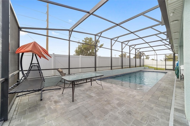 view of swimming pool featuring glass enclosure and a patio