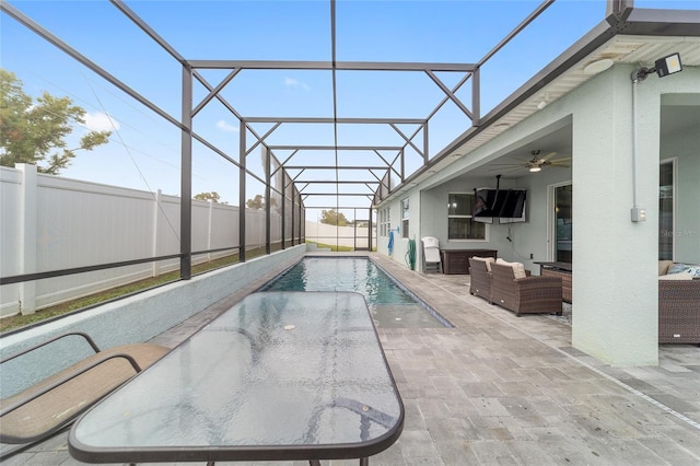 view of pool with ceiling fan, glass enclosure, a patio, and an outdoor hangout area