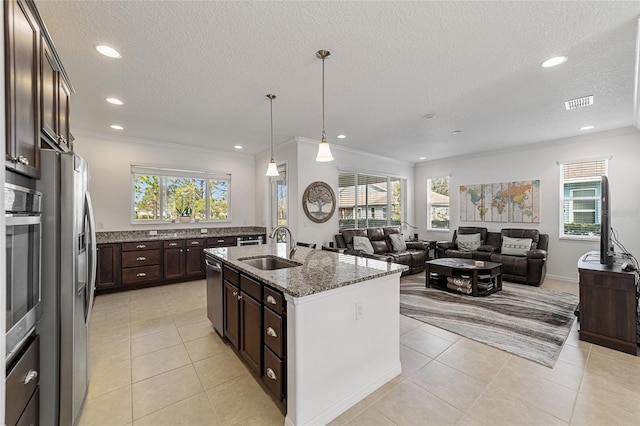 kitchen featuring appliances with stainless steel finishes, a kitchen island with sink, light stone countertops, and a wealth of natural light