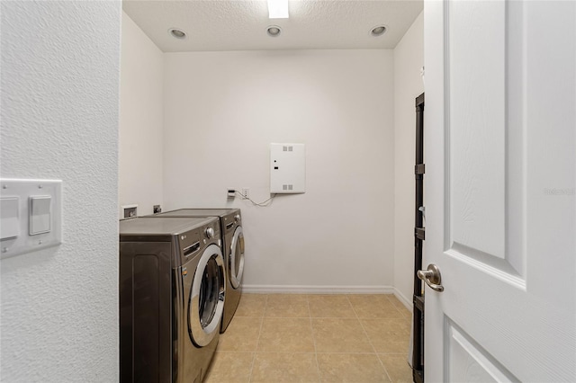 clothes washing area with independent washer and dryer, a textured ceiling, and light tile patterned floors