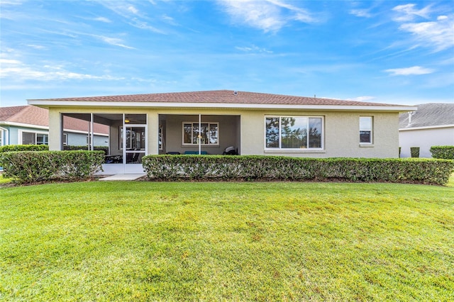 rear view of house featuring a yard and a sunroom