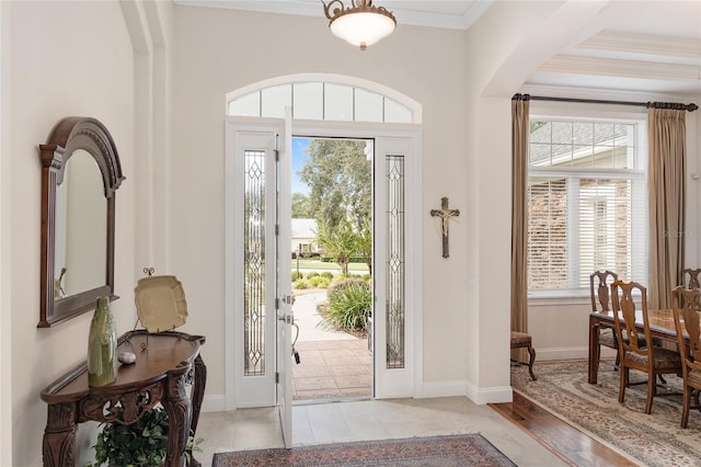 entrance foyer with ornamental molding, light wood-type flooring, and plenty of natural light