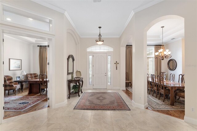 entryway with light hardwood / wood-style floors, an inviting chandelier, and crown molding