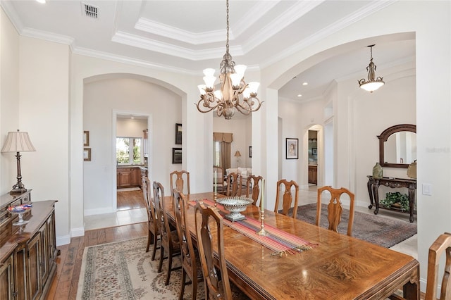 dining room featuring hardwood / wood-style floors, a raised ceiling, and ornamental molding