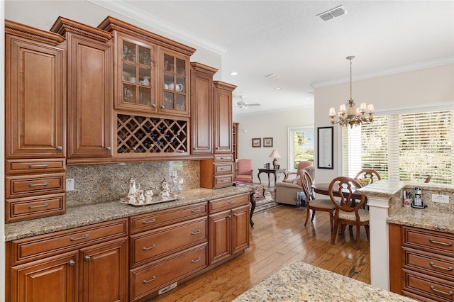 kitchen with light hardwood / wood-style floors, decorative backsplash, pendant lighting, and crown molding