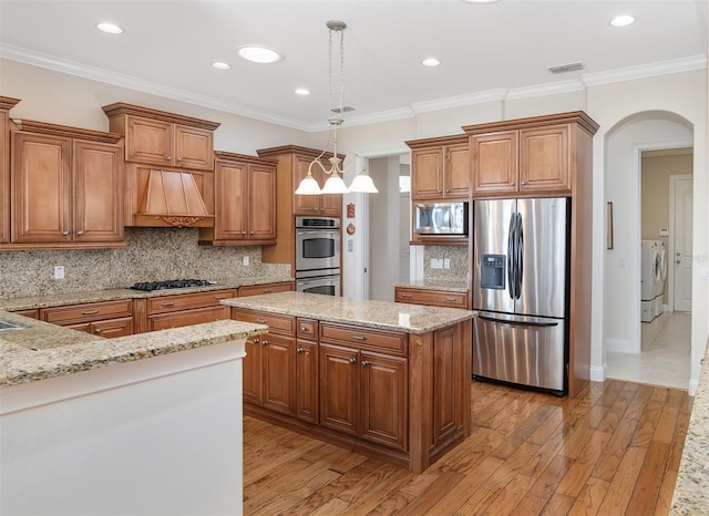 kitchen featuring stainless steel appliances, light hardwood / wood-style floors, custom exhaust hood, crown molding, and pendant lighting