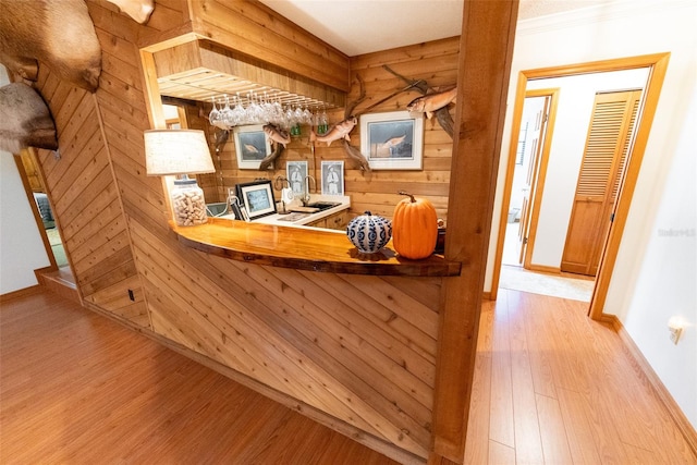 bar featuring light hardwood / wood-style flooring, wood walls, and crown molding