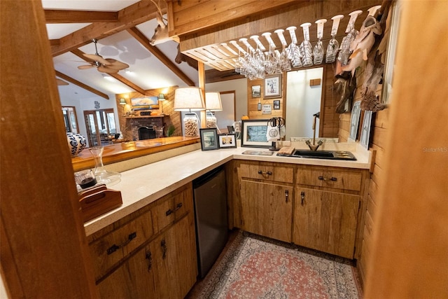 kitchen featuring lofted ceiling with beams, a fireplace, sink, dishwasher, and ceiling fan