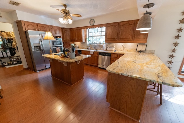 kitchen with stainless steel appliances, a kitchen breakfast bar, hanging light fixtures, a kitchen island, and dark hardwood / wood-style flooring