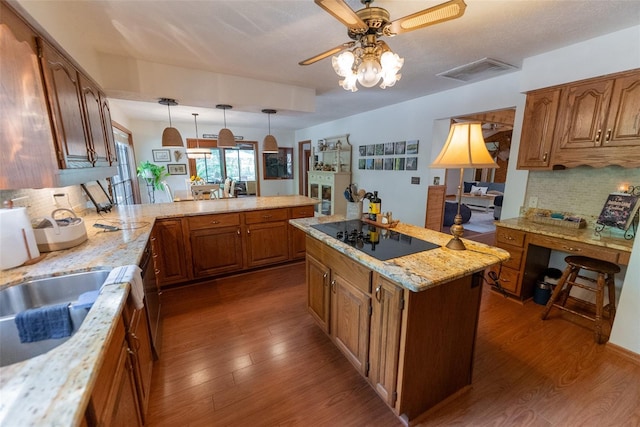 kitchen with black electric stovetop, light stone counters, decorative backsplash, dark hardwood / wood-style floors, and pendant lighting