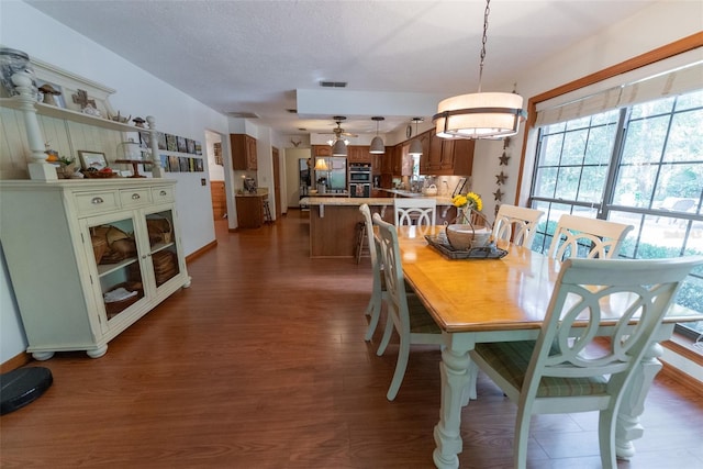 dining space featuring dark wood-type flooring, ceiling fan, and a textured ceiling