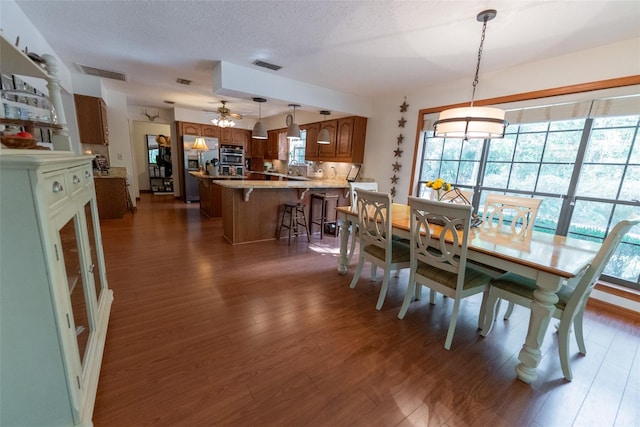 dining area featuring a textured ceiling, dark hardwood / wood-style floors, and ceiling fan