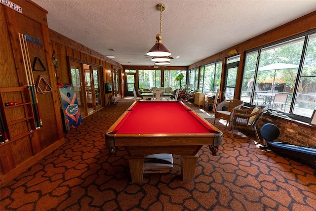 rec room featuring a wealth of natural light, a textured ceiling, wooden walls, and pool table