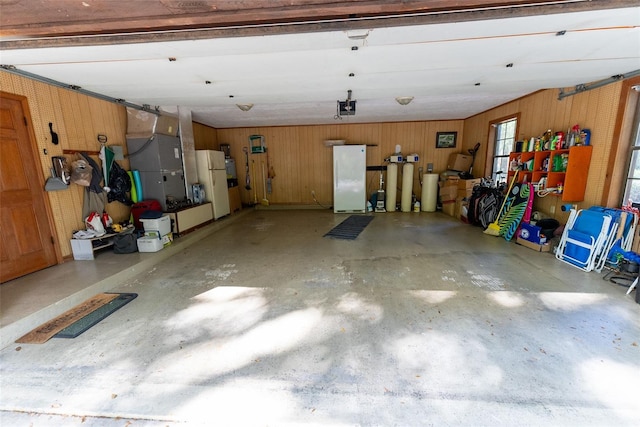 garage featuring a garage door opener, wooden walls, and white refrigerator