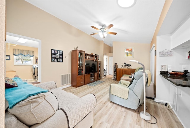 living room with light hardwood / wood-style floors, lofted ceiling, ceiling fan, and washing machine and clothes dryer