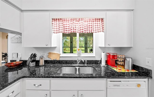 kitchen with white cabinets, white dishwasher, dark stone counters, and sink