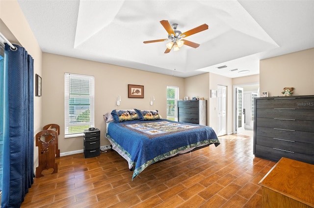 bedroom featuring hardwood / wood-style flooring, ceiling fan, and a raised ceiling