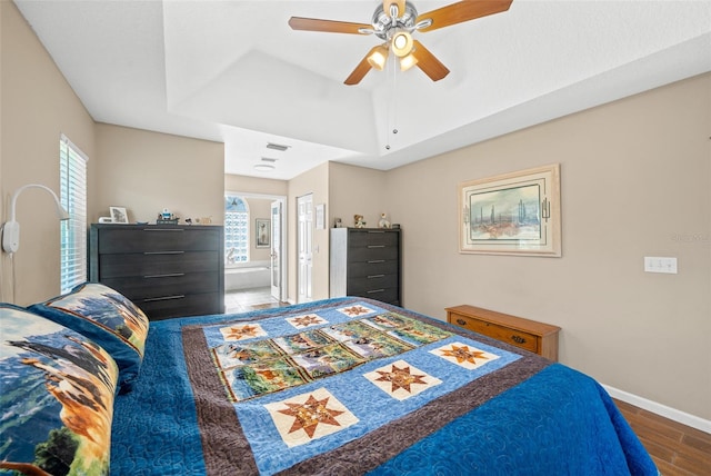 bedroom with connected bathroom, multiple windows, hardwood / wood-style flooring, and ceiling fan